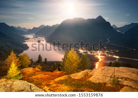 Silvaplana in Switzerland is a beautiful chain of reservoirs surrounded by picturesque rocky peaks. High-altitude lake Hahnensee in the starlight under the moon