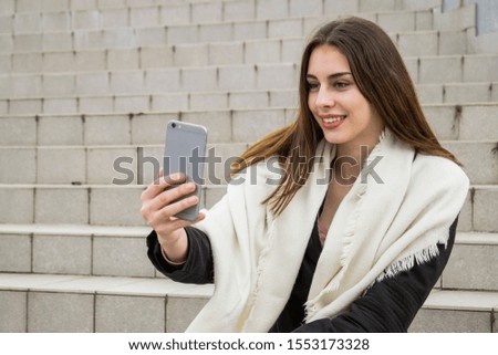 Young woman taking selfie with mobile phone while sitting on stairs