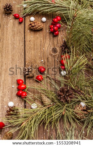 Spirit Christmas background. Fresh dog-rose berries, candies, pine branches and cones, artificial snow. Nature decorations, vintage wooden boards, flat lay, copy space, close up