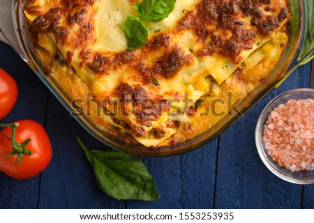 Italian lasagna, on a blue wooden background. Culinary background, Italian recipe book, delicious food. With space for design, top view.