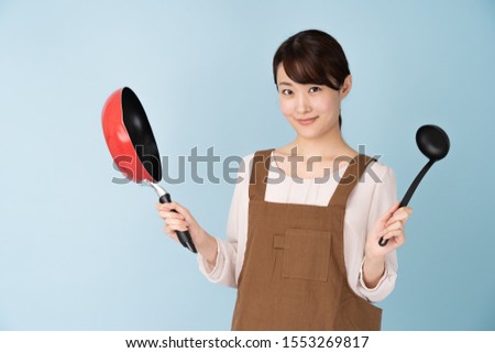 portrait of young asian woman wearing apron on blue background
