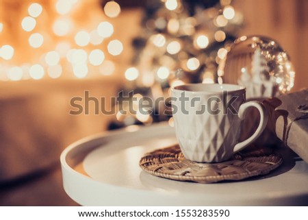 Cup of cocoa with snow globe on blurred lights background. Christmas concept. 