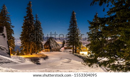 Poiana Brasov, Romania, The hearth of Transylvania, one of the most picturesque Europe`s ski resort.  Wooden chalets and spectacular ski slopes in the Carpathians. View at night.