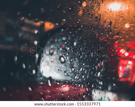 On the night of traffic jam, raindrops cling onto glass window car. 