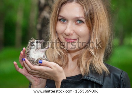 Portrait of a beautiful girl with a hedgehog in his hands. Beautiful woman holding a rodent. A man with a hedgehog in his hands close-up.