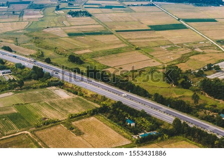 Aerial shot, landscape photography, view from above of a highway going through farmland fields of the countryside in hot sunset evening. Picture taken in Hanoi, Vietnam