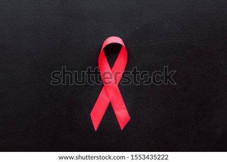 Pink ribbon as symbol of breast cancer awareness on black background top view copy space