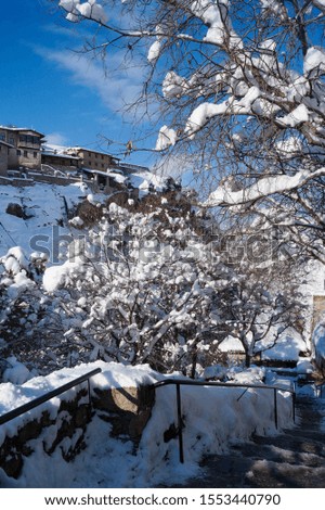 Vertical photo. Dramatic winter landscape with mountain after snowfall. Monastery Meteora background, snow cowered trees foreground and stairs in Kalambaka, Greece, Europa. UNESCO list. 