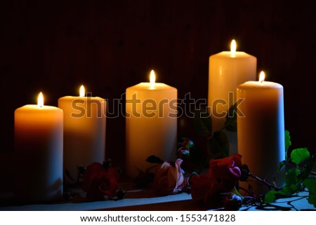 Burning candles and roses on a dark background. Posthumous burning candles. Mourning picture with place for text.