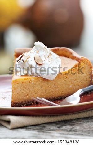 A slice of Pumpkin Cheesecake Pie with homemade whipped cream, alomonds and pumpkin spice. Extreme shallow depth of field.