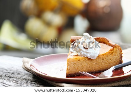 A slice of Pumpkin Cheesecake Pie with homemade whipped cream, almonds and pumpkin spice. Extreme shallow depth of field.