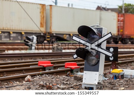 Signaling device at the railroad tracks and the train with containers.