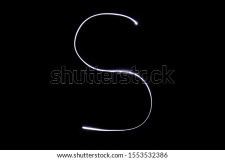 Alphabet made of neon light on a black background. Isolated top view, letter s