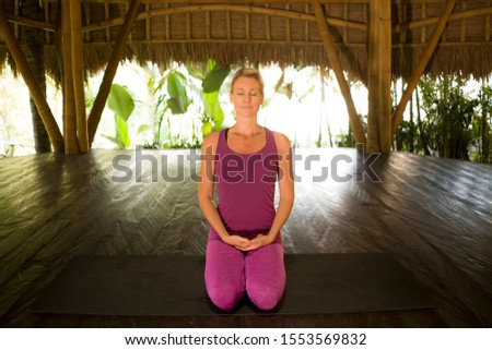young happy and beautiful blond American woman doing yoga workout in Bali at exotic bamboo hut opened to the forest in fitness and healthy lifestyle enjoying retreat in balance and harmony
