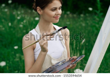 young woman in a forest glade with white canvas easel
