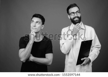 Young bearded Persian man doctor with young Hispanic man patient