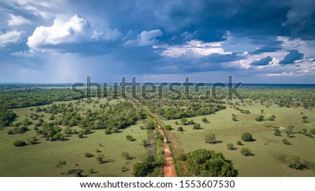 Aerial view of Transpantaneira dirt road with dramatic sky and rain crossing the typical landscape in North Pantanal Wetlands, Mato Grosso, Brazil