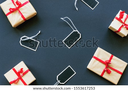 View from above of boxes with gifts and price tags on black background. Flat lay, Black friday sale concept.