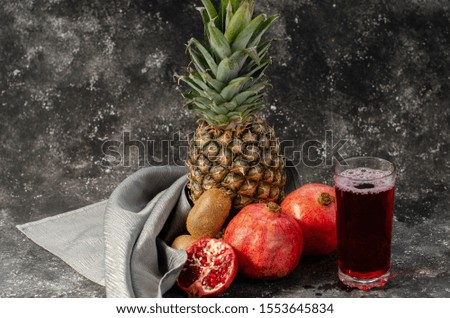 fruits, a pineapple,  pomegranate and kiwi on a gray background