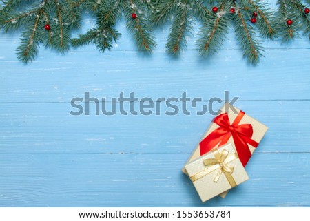 Two gift boxes on a blue background. There is a place for inscriptions and advertising. Christmas tree branches with red berries on top.
