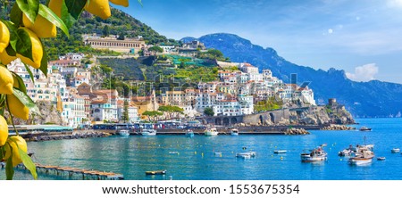 Panoramic view of beautiful Amalfi on hills leading down to coast, Campania, Italy. Amalfi coast is most popular travel and holiday destination in Europe. Ripe yellow lemons in foreground. Royalty-Free Stock Photo #1553675354