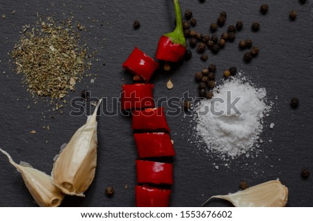 black background for recipes and menus with red hot pepper and spices. red hot pepper sliced ​​on a black stone board with spices