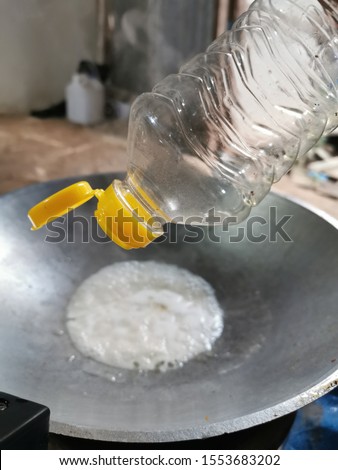 The picture is about to pour oil from a clear bottle into the pan.