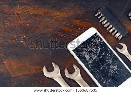 Smartphone repair concept. Damaged display of smartphone and tools