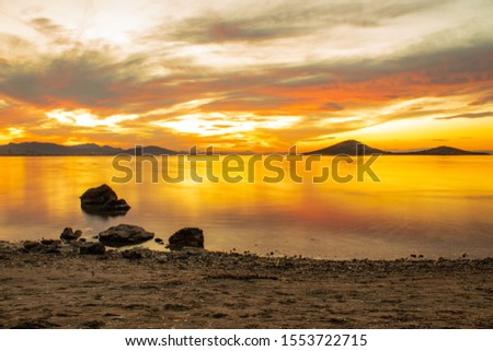 Rocks in the see during the sunset. Orange sunset in La Manga del Mar Menor in Spain.