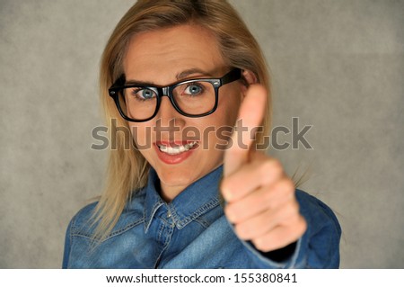 Beautiful blond woman with geek hipster glasses with thumb up showing appreciation