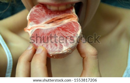 girl eating red grapefruit, a natural antioxidant. man eating tasty, fresh grapefruit. citrus fruit, a source of vitamin C. beautiful, simple photo with place for captions, words. prevention of colds.