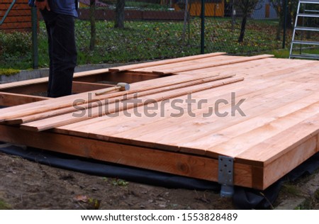 Handy carpenter installing wooden planks during flooring works outside the new house. Czech republic, Europe.