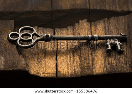 Old ornate skeleton key on rough wood background Royalty-Free Stock Photo #155386496