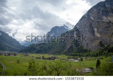 Beautiful panorama view of mountain and houses in small village in rural area of Switzerland on cloudy sky background with copy space
