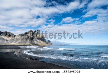 vestrahorn in southern Iceland, mirroring in calm water over black volcanic beach, landscape photography 