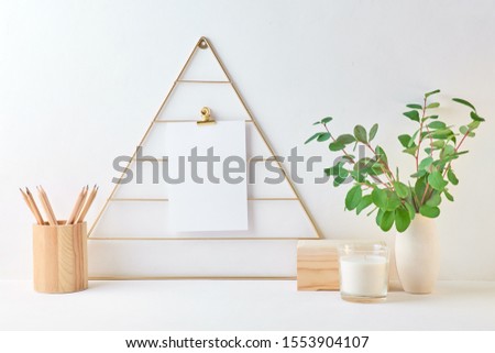 Home interior with decor elements. Mood board with empty card, branches with green leaves in a vase, interior decoration