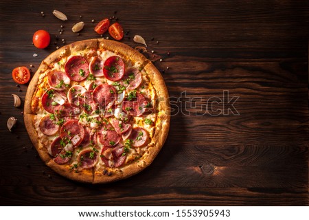 Pizza with salami, ham, bacon, garlic and fresh herbs. Rustic style. Top view. Copy space.