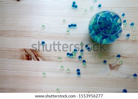 Hydrogel for plants in transparent modern glass vase, scattered on the wooden table, home design, template, card, picture for web, cover, magazine