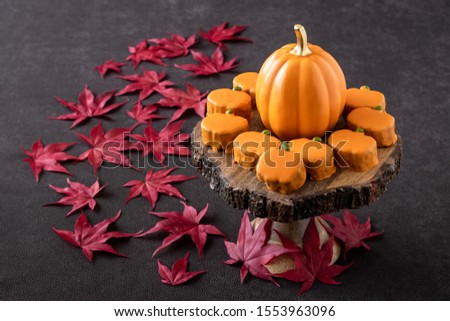 Happy Thanksgiving, small pumpkin cakes, orange ceramic pumpkin on a wooden cake stand, red maple leaves
