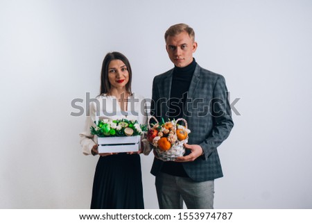 A guy with a girl holding a bouquet of flowers. Images of young teachers. Against the background of a gray wall.