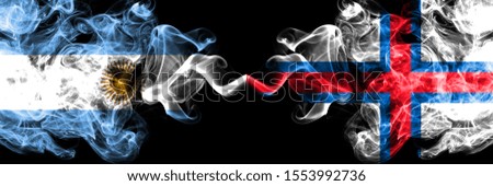 Argentina vs Faroe Islands smoky mystic fire flags placed side by side. Thick colored silky abstract smoke flags concept