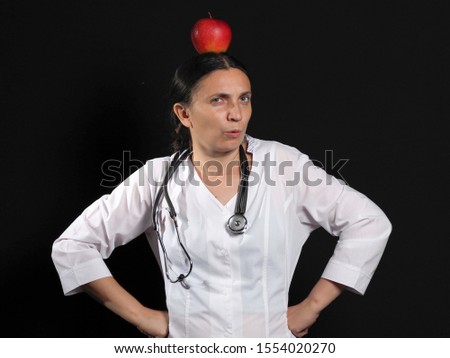 Doctor woman emotionally posing with Apple in hand on black background 