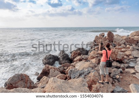 Attractive mature traveler woman use mobile phone take a photo of beautiful seascape. Copy space.