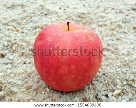 One red apple placed on th sand.