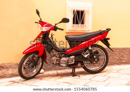 Moped, red scooter stands parked against the wall of the house Royalty-Free Stock Photo #1554060785