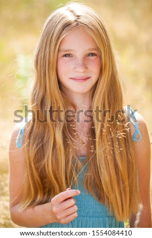 Portrait of a beautiful young blonde little girl on the background of summer park