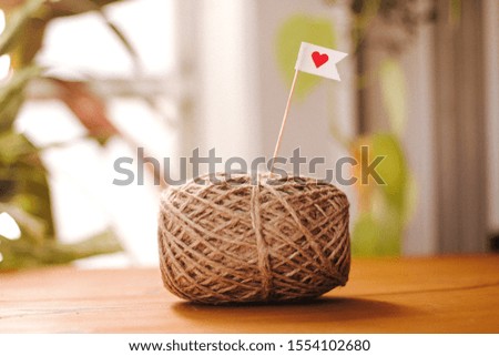 ball of sisal thread with heart sign on wooden table
