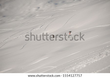Man and woman riding down the hill on the snowboard in the popular tourist resort Gudauri in Georgia