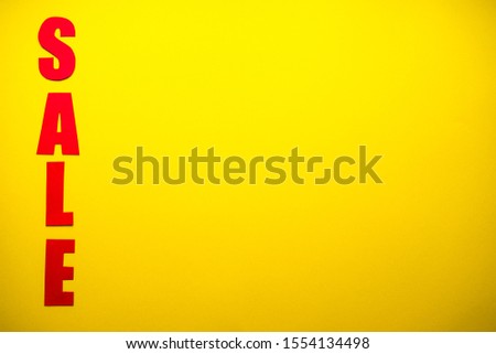 Black friday concept.
Sale in red letters on a yellow background with confetti, place for text top view.