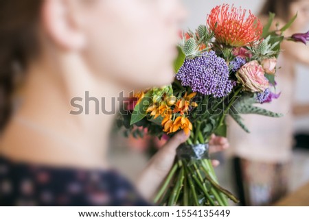 A girl holds a bouquet of different colored flowers in her hand. Florist training workshop on creating flower bouquets. Floristics Studio.